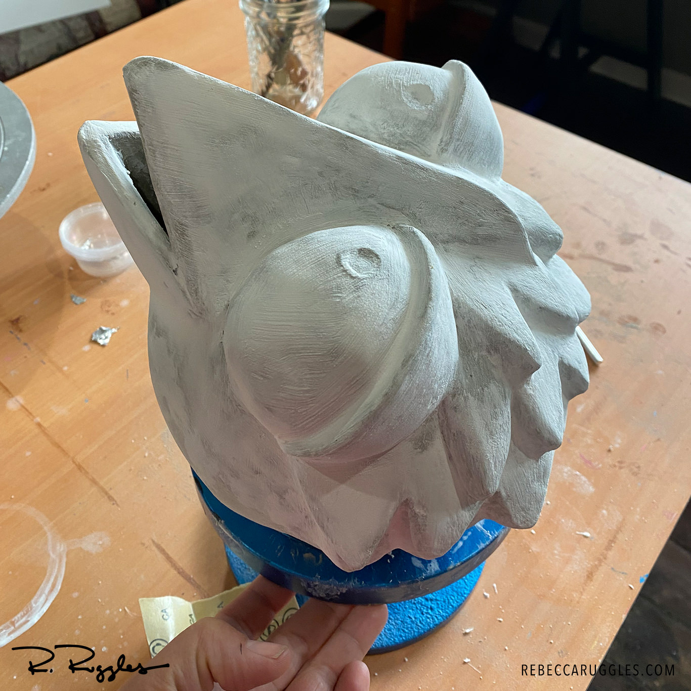 Smoothing the bird sculpture with sanding and joint compound.