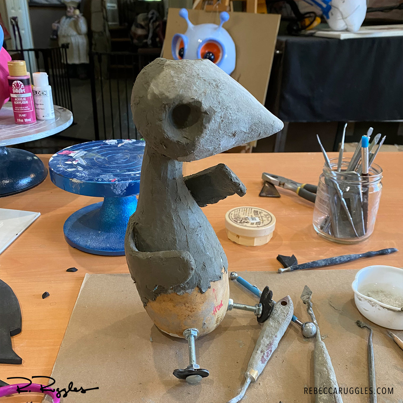 Applying clay to my little bird sculpture.