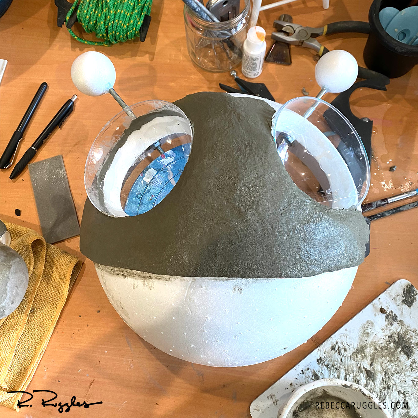Adding wet concrete paper clay to the alien head armature with trowel.