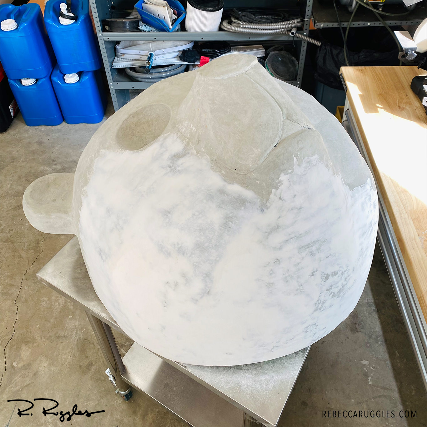 Troweling joint compound onto the giant panda head sculpture to smooth the surface.